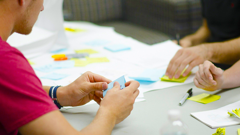 Trois personnes autour d'une table écrivant sur des post-it © StartupStockPhotos/Pixabay